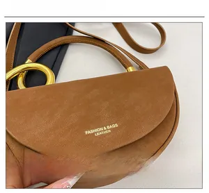 Close-up of caramel leather handbag with gold ring handle and textured grain finish