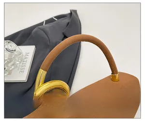 Detail of brown suede handbag featuring elegant gold metal ring and leather handle