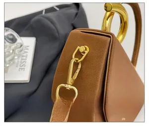 Detailed close-up of premium gold-toned metal hardware and brown pebble grain leather handbag