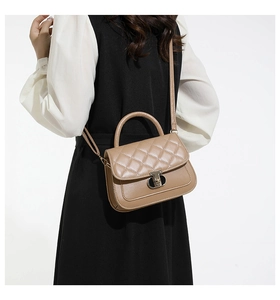 Close-up of stylish quilted light brown crossbody bag with metal buckle and shoulder strap