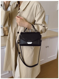 Détail du sac à main noir montrant la texture en similicuir et la boucle argentée