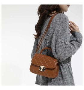 Detail of brown quilted leather handbag with gold CD clasp and stylish shoulder strap