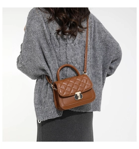 Detail van een bruine gewatteerde crossbodytas met gouden draaisluiting bij een model