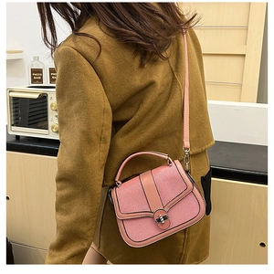 Detailed close-up of pink leather handbag featuring a metal turn-lock and stylish top handle