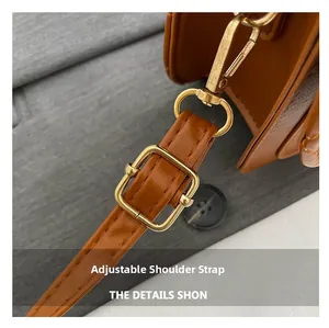 Detail van verstelbare karamel lederen schouderriem met goudkleurige gespsluiting