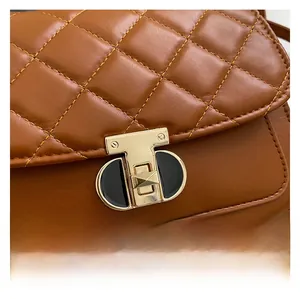 Detail van een karamelkleurige gewatteerde leren handtas met vintage metalen T-sluiting