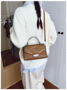 Sac à bandoulière en cuir marron porté par un mannequin en pull en maille blanc