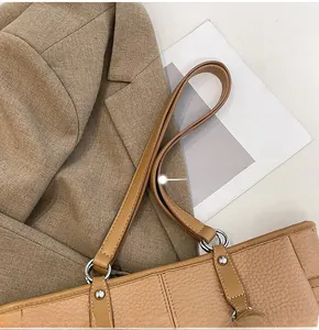 Detail of brown pebbled leather tote bag with silver hardware and smooth stitching