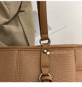 Detail of silver rivets and metal ring connecting the leather strap of a brown tote bag