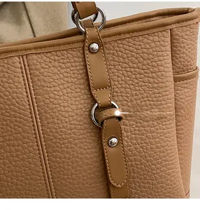 Close-up of brown litchi pattern leather tote bag with silver ring and rivet details