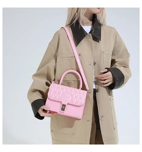 Detail of pink quilted handbag showing wave stitching, round FASHION logo, and gold lock