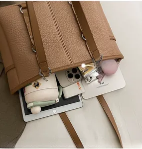 Macro view of large caramel brown tote bag showing spacious interior with iPad and phone