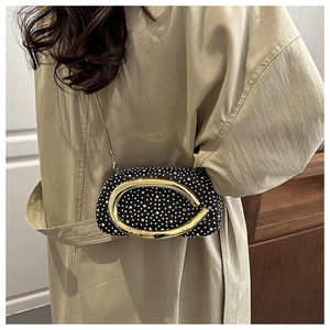 Detail of a luxury black rhinestone evening bag with oversized gold D-ring hardware and chain