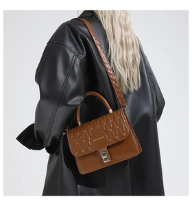 Detail of caramel brown crossbody bag with quilted texture and golden twist-lock closure