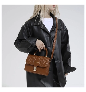 Brown crossbody bag featuring wave quilted texture and gold turn-lock with fashion logo
