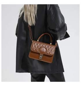 Detail of brown quilted leather crossbody bag with gold Fashion logo and metal lock