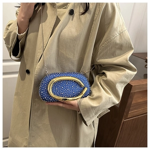 Blue beaded evening bag with signature gold metal clasp and chain strap on a trench coat