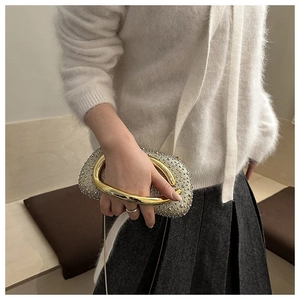 Detail of evening clutch with gold metal handle and sparkling rhinestone surface