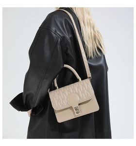 Quilted beige crossbody bag with top handle and FASHION logo shown on model