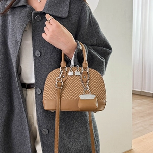 Brown patchwork shell bag with woven texture and leather details on wool coat