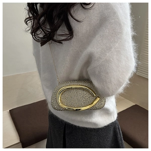 Luxurious silver rhinestone evening bag with gold C-shape hardware worn by model