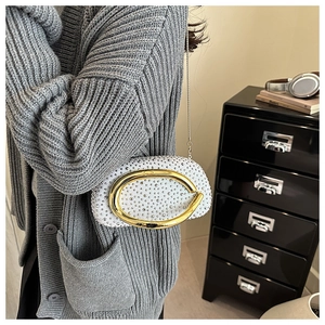 Detail of white crystal clutch bag featuring sparkling rhinestones and gold oval buckle