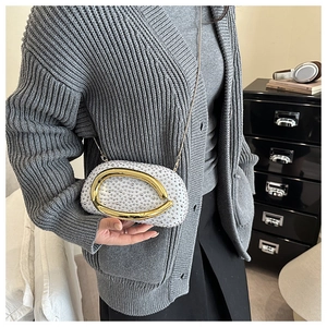 Detail of white rhinestone crossbody bag with oversized asymmetric gold metal handle