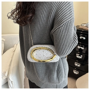 Detail of white acrylic rhinestone evening bag with gold chain strap on a model