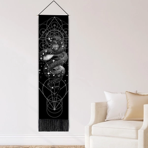 Black snake tapestry with sacred geometry and fringe hanging on a white living room wall