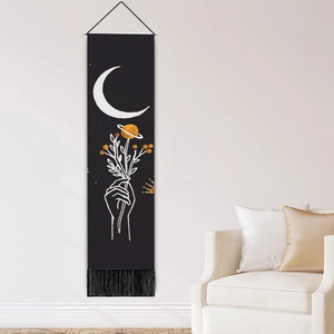 Minimalist moon phase tapestry with hand holding flowers and black tassels on white wall