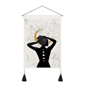 Detail of bohemian wall tapestry with sun moon pattern and black tassels on beige fabric