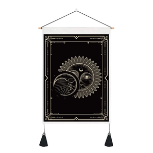 Detail of tarot tapestry featuring sun and moon graphics with golden tassels and wooden rod