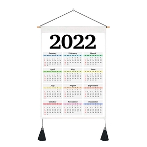 Detail of 2022 calendar fabric wall hanging with wooden rod and black tassels