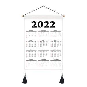 Detail of 2022 fabric calendar featuring wooden hanger and black decorative tassels