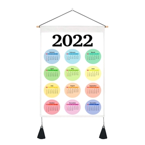 Detail of 2022 fabric wall calendar with wooden pole, black rope and elegant tassels