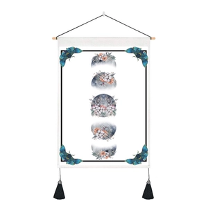 Detail of bohemian moon phase tapestry with floral motifs and wooden hanging rod