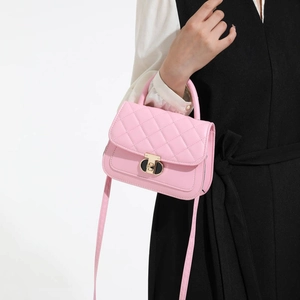 Pink quilted tote bag with gold clasp and crossbody strap held by a model