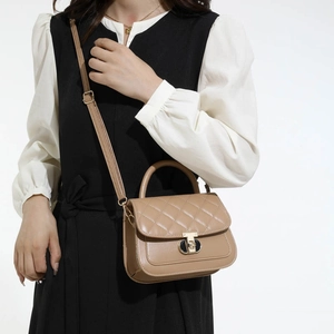 Stylish camel quilted handbag with metal lock and adjustable strap in side view