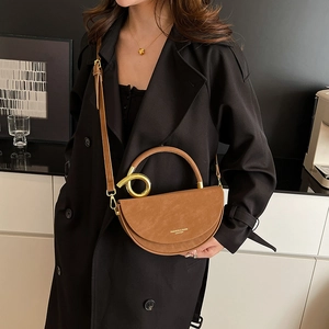 Brown half-moon crossbody bag with golden round handle and suede-like finish for women