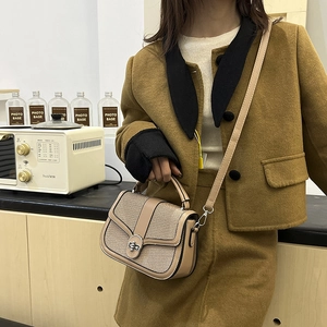 Women's chic woven tote bag with brown leather trim and metal lock in home setting