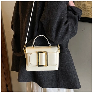 Detail of white square handbag with gold buckle, styled on a textured grey coat