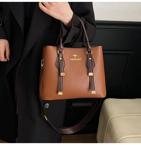 Detail of brown pebbled leather tote bag with gold kangaroo logo on black coat