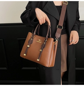 Detail of caramel leather tote bag with gold kangaroo logo and wide fabric strap