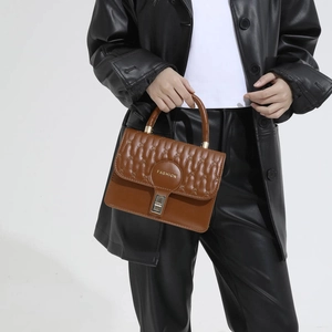 Brown quilted crossbody bag with top handle and gold fashion lock in minimalist style