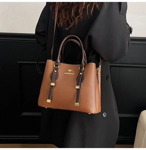 Detail of warm brown leather tote bag with gold kangaroo logo on a black coat
