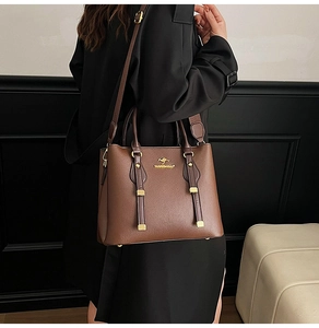 Detail of dark brown leather tote bag with golden kangaroo logo and textured finish