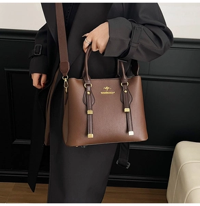 Detail of brown lychee texture leather tote featuring golden kangaroo logo and wide strap