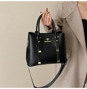 Close-up of black lychee texture leather handbag with gold kangaroo logo and metal hardware