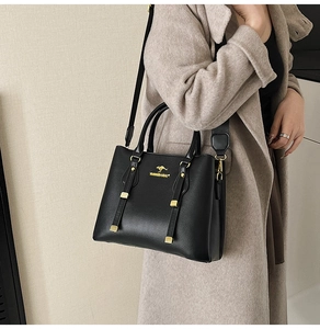 Detailed view of black litchi leather tote featuring golden kangaroo logo and hardware