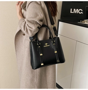 Detail of black pebbled leather tote bag with gold kangaroo logo and wide shoulder strap